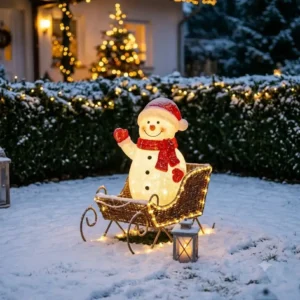 Ein strahlender LED-Schneemann im Schlitten als gartendeko wetterfest weihnachtsfiguren im winterlichen Garten